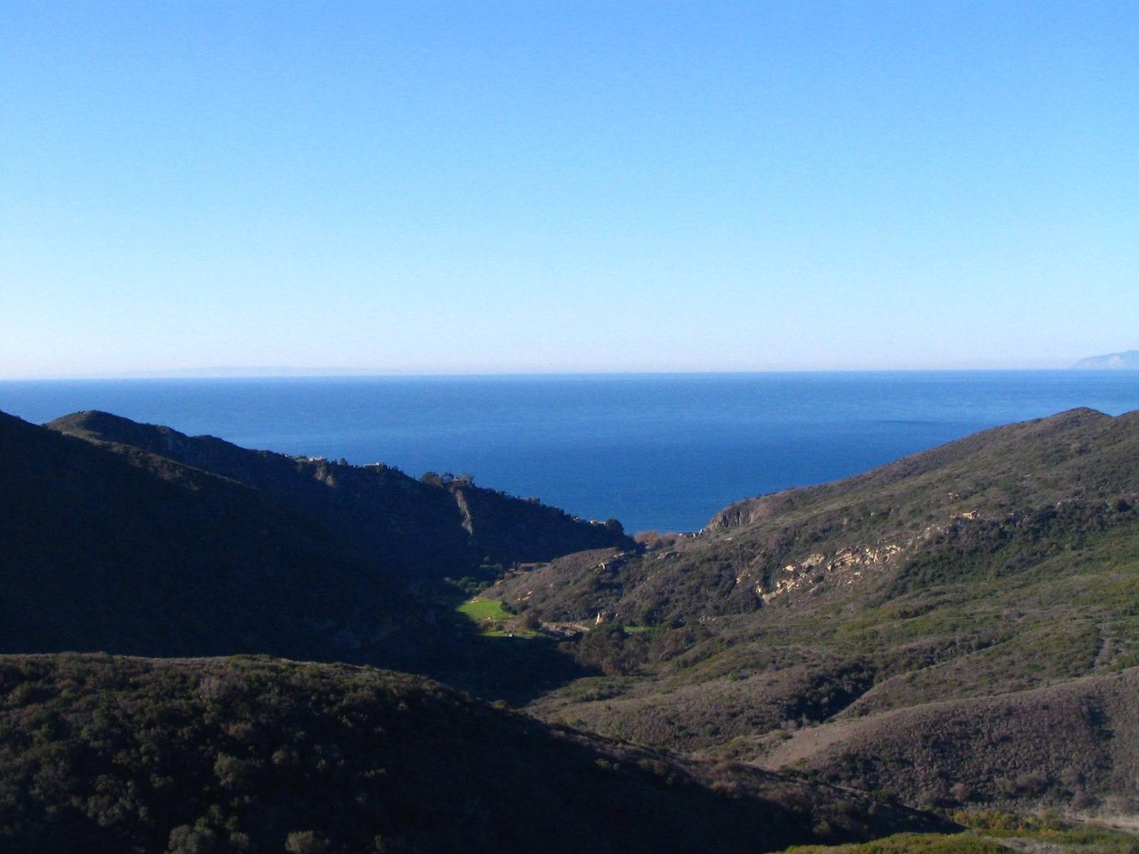 The mouth of Aliso Canyon opens toward the Pacific, with wildland ridges rising above the canyon floor.