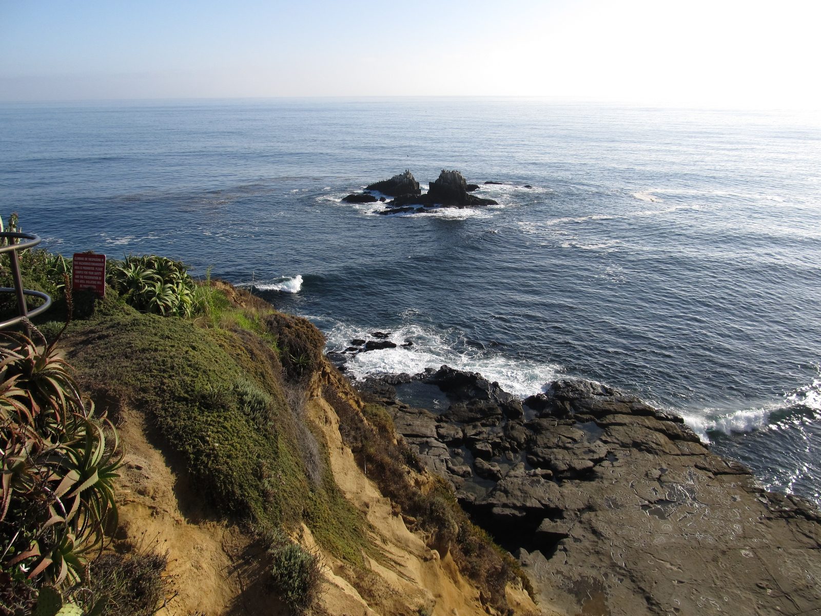 The rocky point and warning sign at Crescent Bay Point Park, the cliffside setting for the viral video.