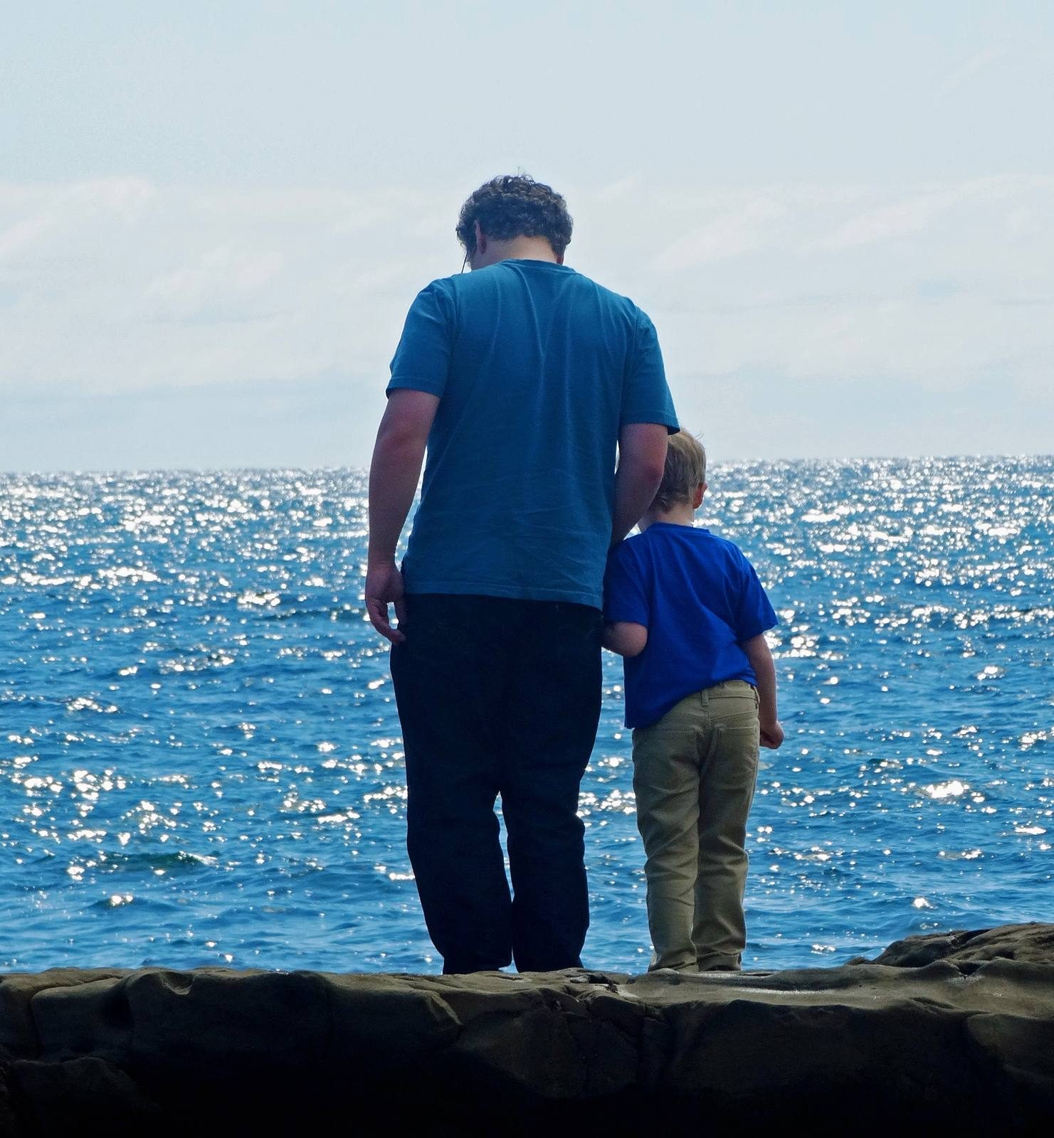 A father and son take in the ocean from the rocks at Laguna Beach.