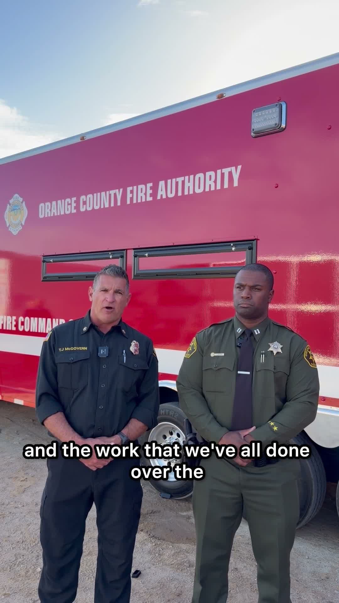 Fire authority and sheriff officials deliver the Saturday evening repopulation update in front of an Orange County Fire Authority command trailer. Evacuation orders were lifted that evening, with two closures left standing.