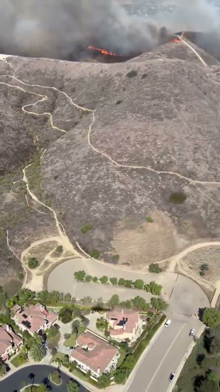 Homes sit below the burning hillsides of San Clemente in a helicopter view from Friday, the day the Norte Fire started. Containment reached 92 percent by Tuesday evening.