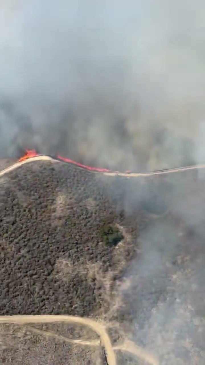 A line of flame runs along a ridge road through drifting smoke on Friday. Crews spent Tuesday patrolling the perimeter and checking for remaining heat.