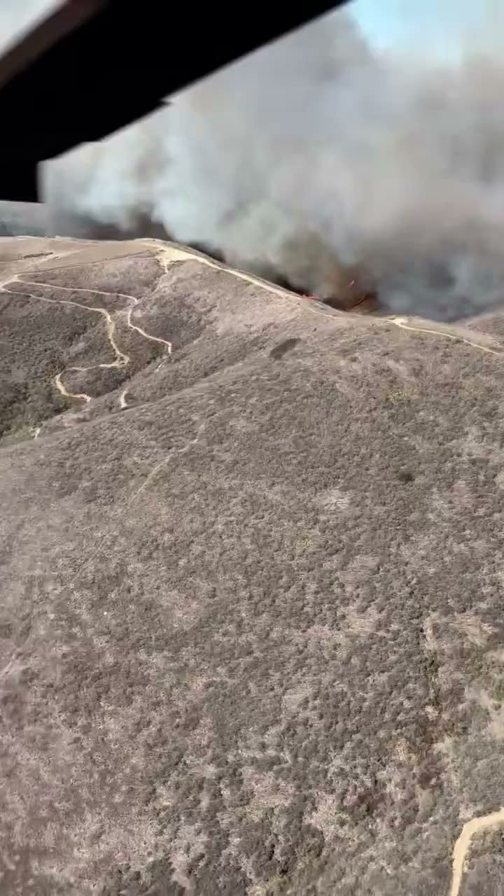 Smoke rises over brush covered hillsides in a helicopter view from Friday. The burned area held at 570 acres while crews moved on to suppression repair this week.