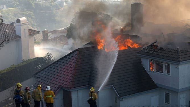Firefighters spray water on a burning home in San Juan Capistrano on Friday as the Norte Fire moved through the neighborhood. By Saturday evening, containment had reached 25 percent.