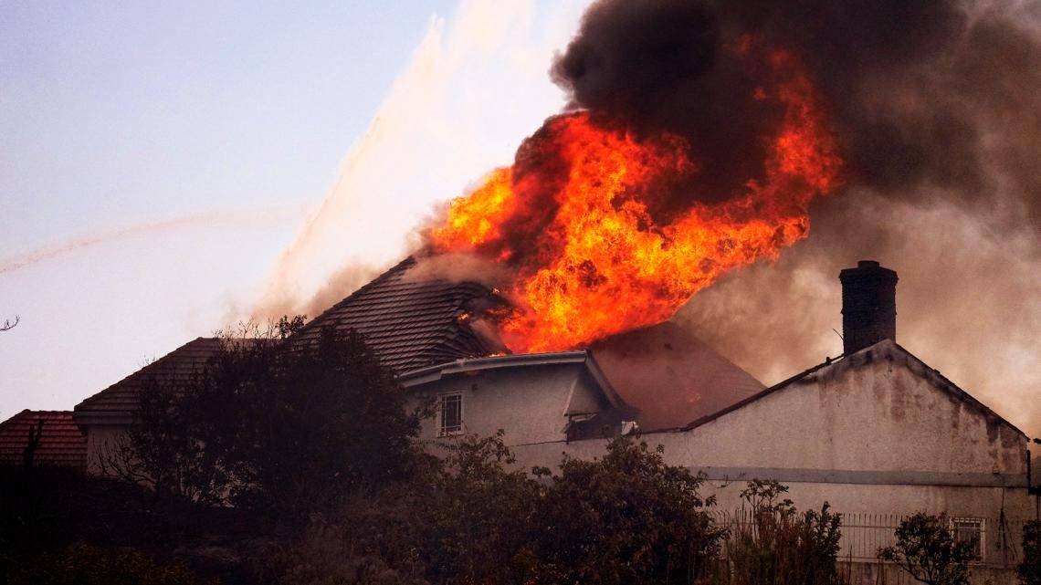 Flames tear through the roof of a home in San Juan Capistrano on Friday as the Norte Fire moved through the neighborhood. Six homes were destroyed or damaged.