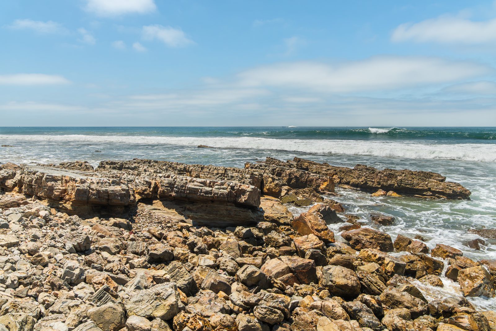 Surf breaks over the layered rocks at Pelican Point in Crystal Cove State Park. The crack in the bluff below the highway followed days of powerful surf and high tides on this coast.