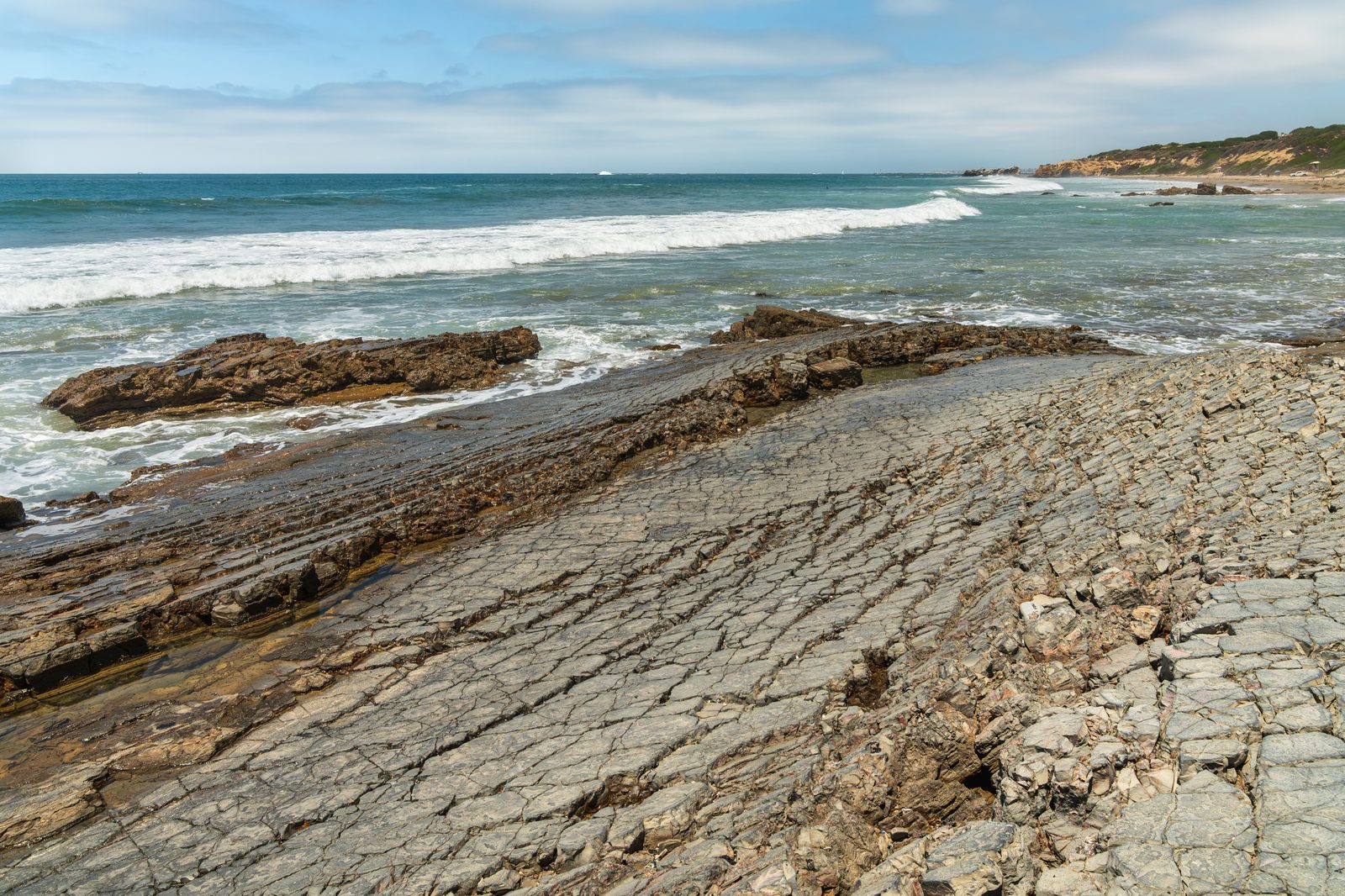 The cracked rock shelf at Pelican Point, looking north along the Crystal Cove coast. Caltrans will cover the crack below the highway, armor the base of the slope with large rocks, then design a longer term fix with State Parks.