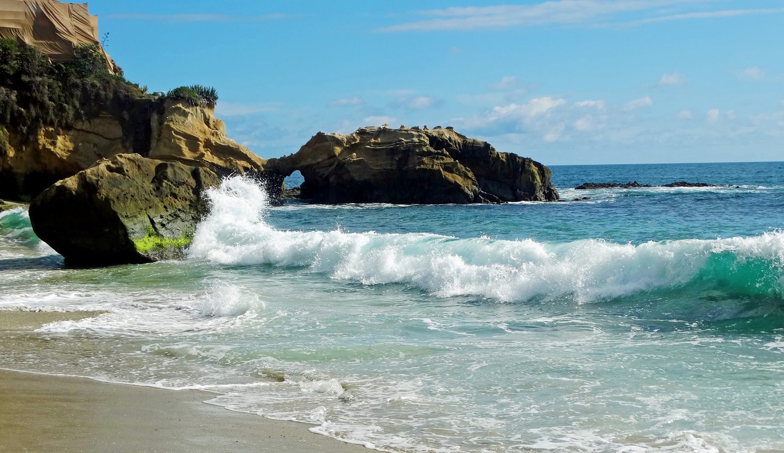 Waves break at Natural Arches in Laguna Beach. Sunday morning brought a lighter swell than forecast, but coastal flood alerts remain in effect into Tuesday.